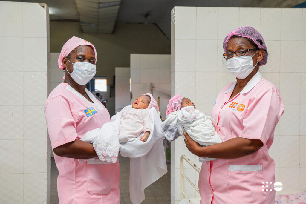 Two midwives hold newborns.