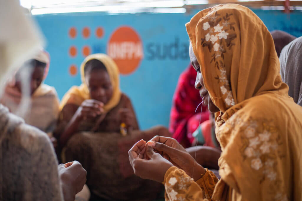 Women and girls fleeing violence from the war in Sudan work on craft activities and receive psychosocial support at a UNFPA safe space.