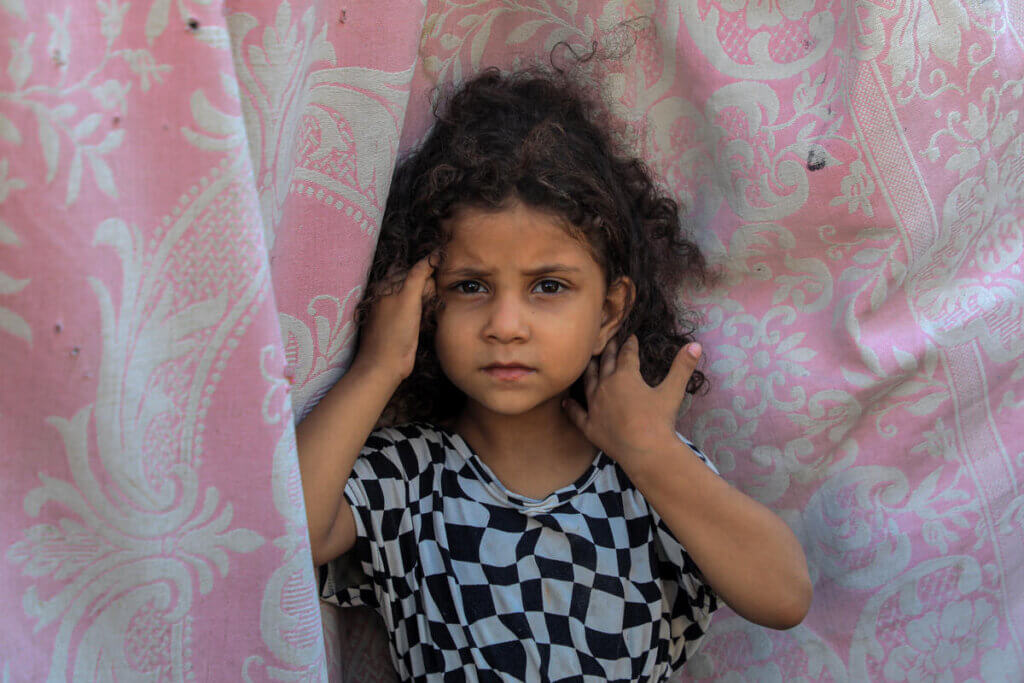 Girl looks at camera in displacement camp in Gaza.