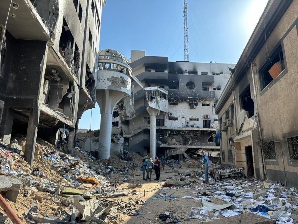 UN workers walk through rubble of hospital in Gaza.