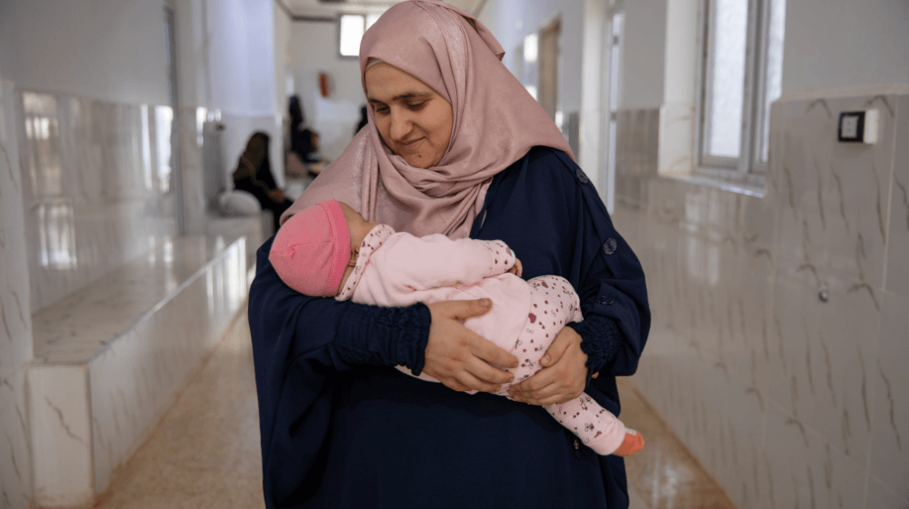 Mother holds newborn daughter after receiving mental health services throughout pregnancy.