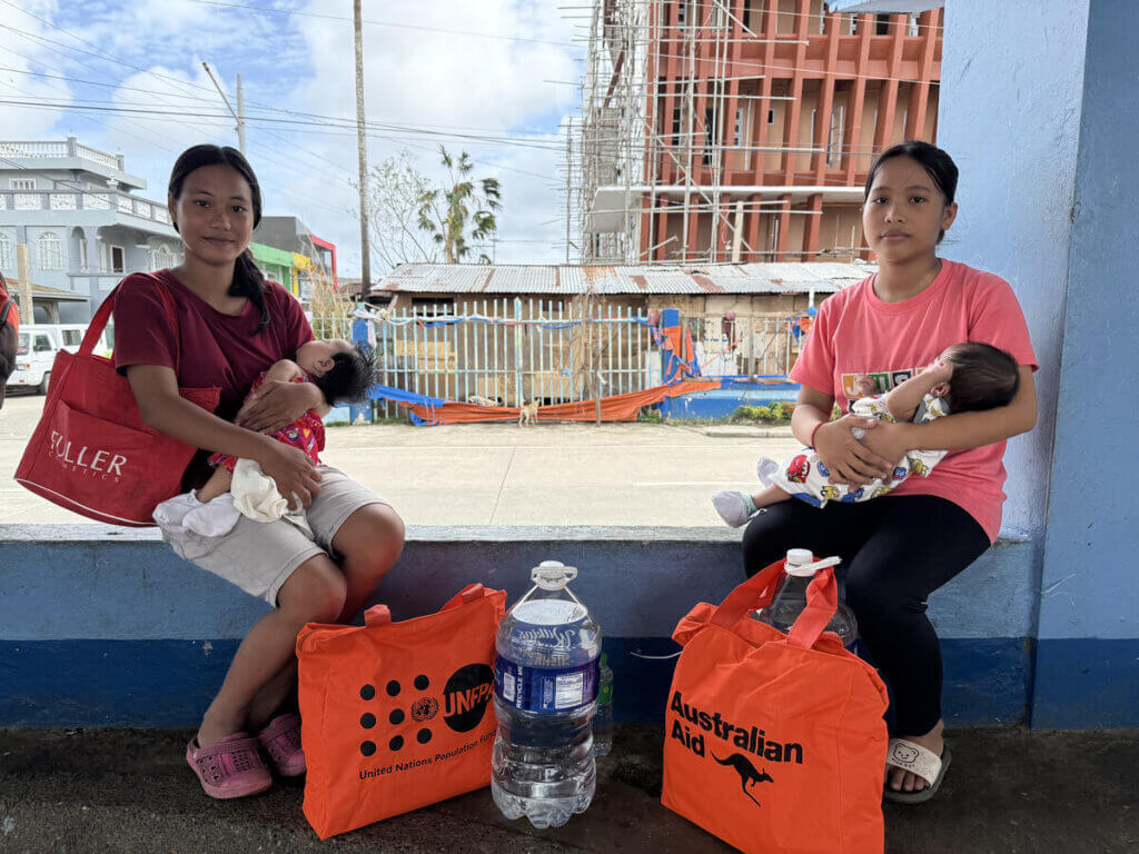 Two mothers and their babies pose with their UNFPA Dignity Kits.