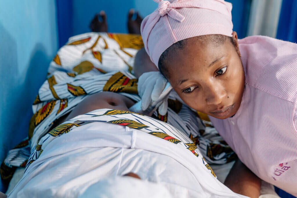 Midwife Major Kangah uses a Pinard stethoscope to check fetal heart rate and vital organs at a UNFPA health center.