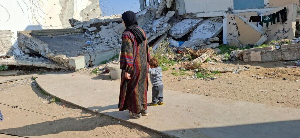 A woman and child walk through the rubble in Gaza City